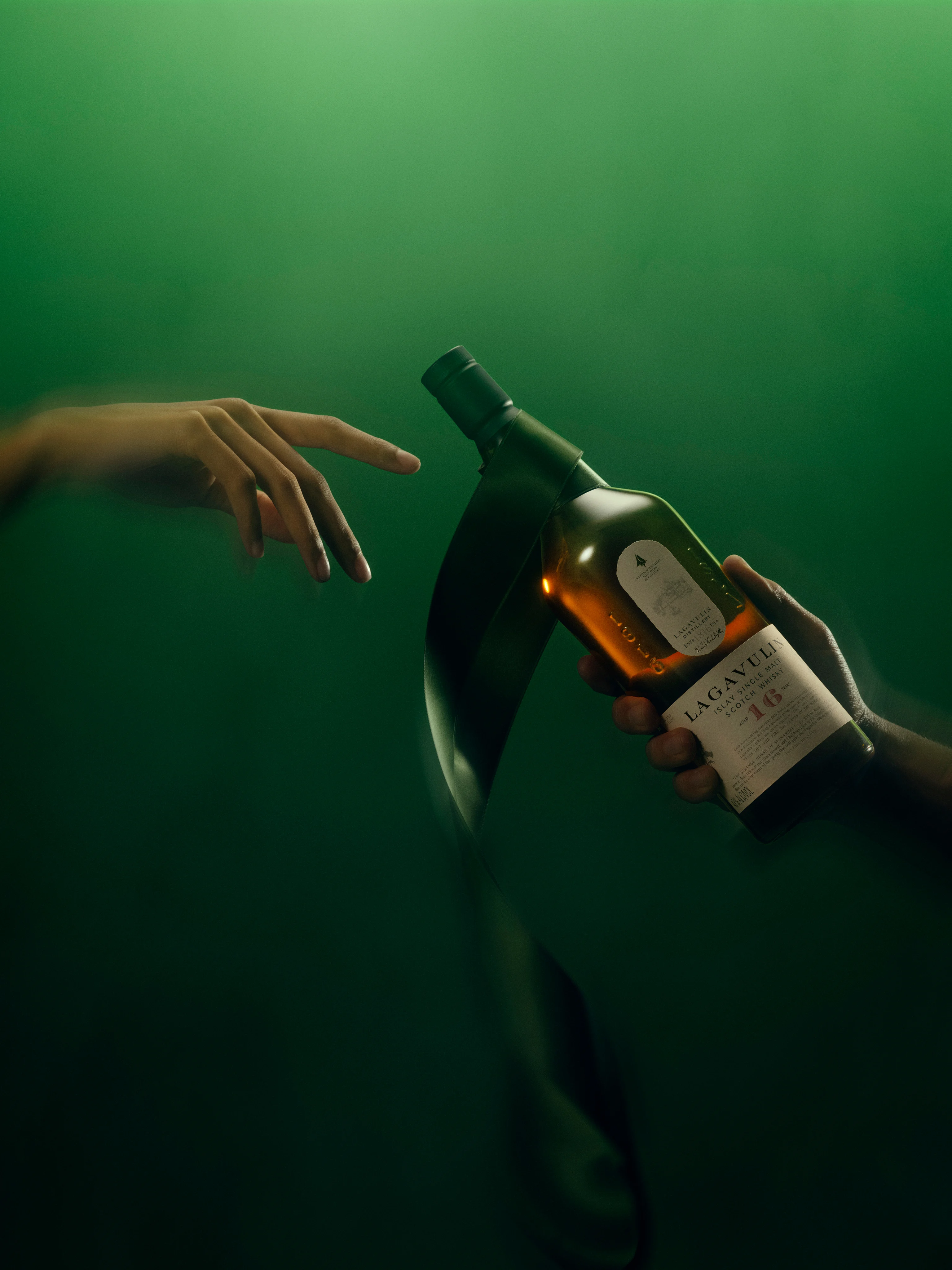 Finger reaching out to touch Lagavulin bottle  object-cover object-center absolute inset-0 h-full w-full h-full w-full object-cover object-center bottle from Lagavulin Distillery